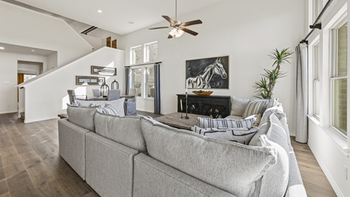 living room with ceiling fan next to stairs