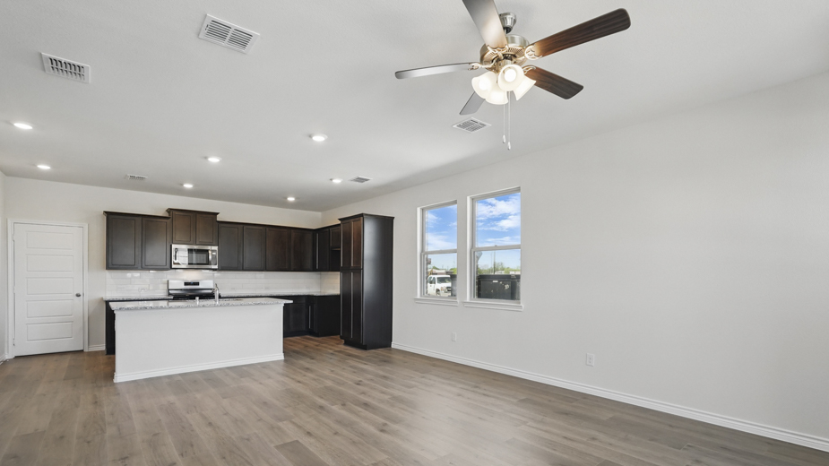 open concept living area with hardwood floors and natural light coming from the windows and white walls
