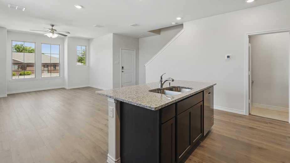 kitchen area with hardwood floors light colored counters dark cabinets and kitchen island