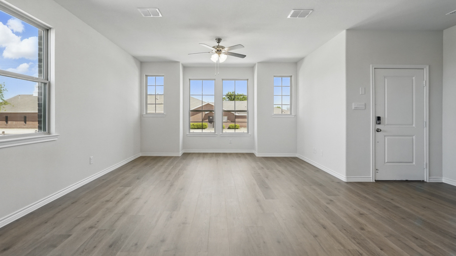 open concept living area with hardwood floors and natural light coming from the windows and white walls