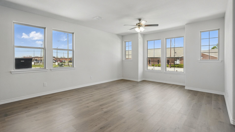 open concept living area with hardwood floors and natural light coming from the windows and white walls