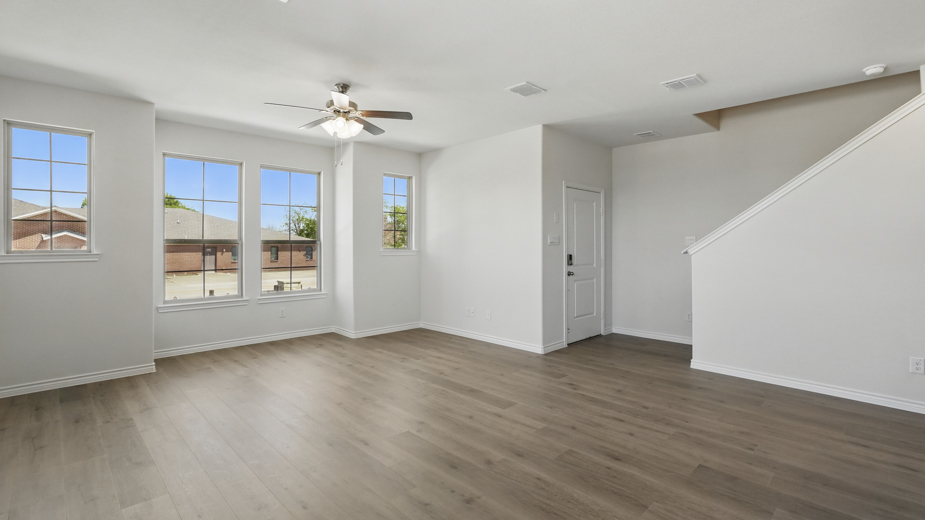 open concept living area with hardwood floors and natural light coming from the windows and white walls