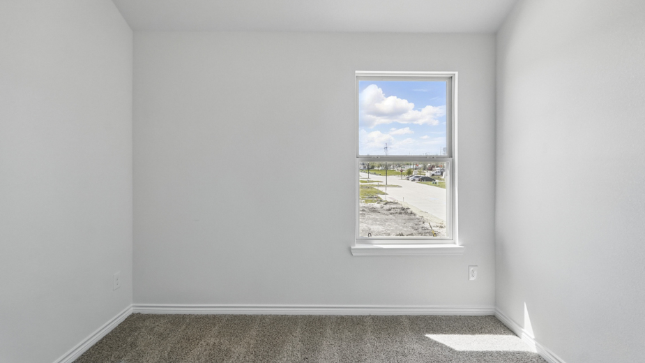 secondary bedroom with light colored carpet white walls and natural light coming from large window