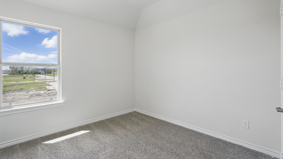 secondary bedroom with light colored carpet white walls and natural light coming from large window