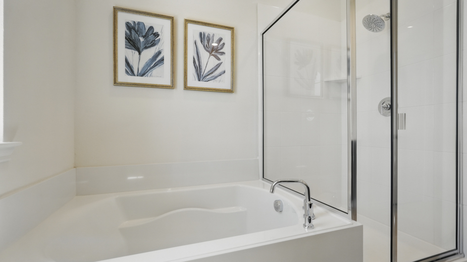 primary bathroom with light colored floors and white bath tub