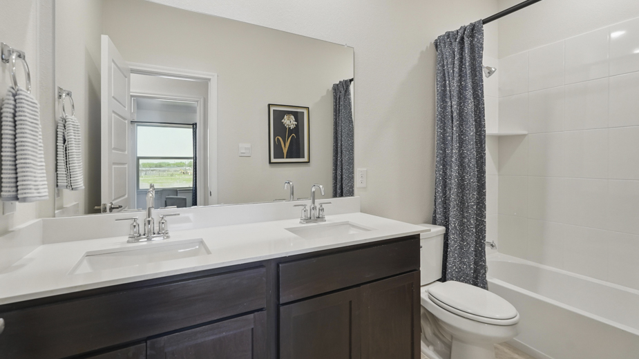 secondary bathroom with white counters and dark cabinets