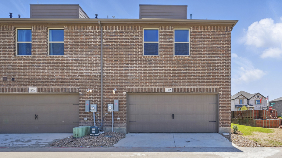 exterior of the back of the townhome with large windows and garage entry