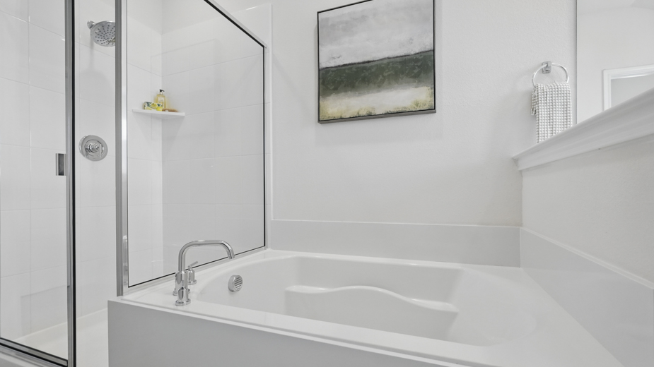 primary bathroom with light colored floors dark cabinets and white counters