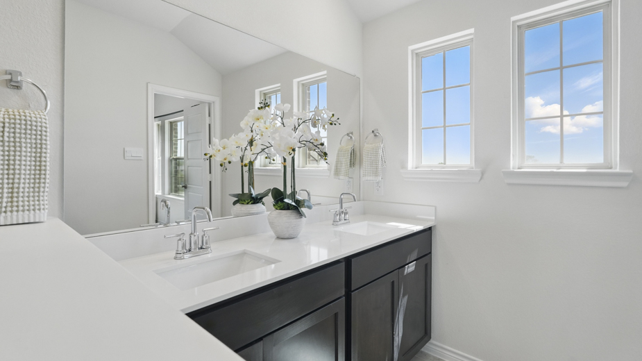 primary bathroom with light colored floors dark cabinets and white counters