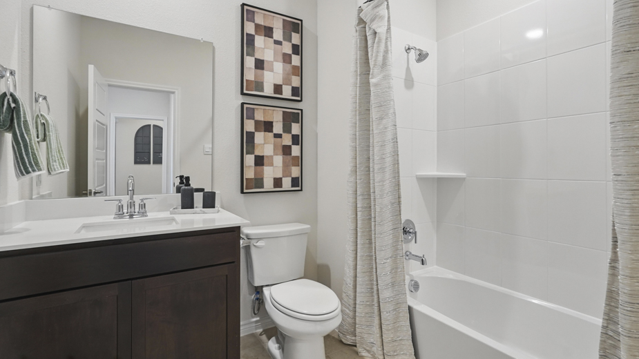 secondary bathroom with white counters and dark cabinets