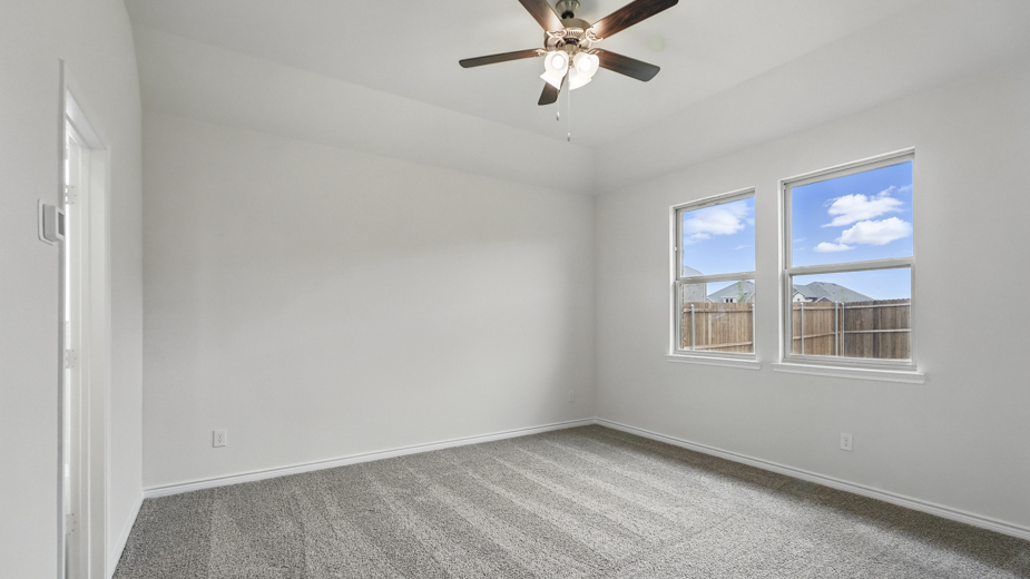 Bedroom with carpeted floors and large windows.