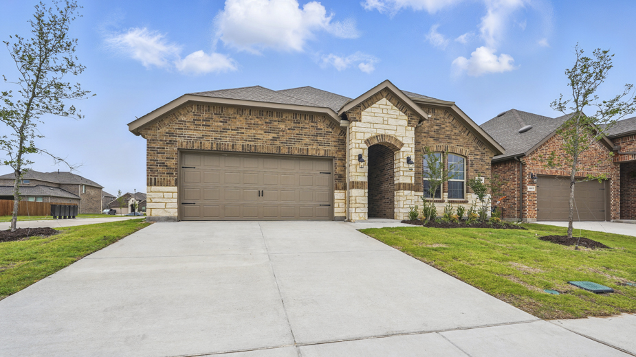 Front exterior of home with two car garage and brick siding.