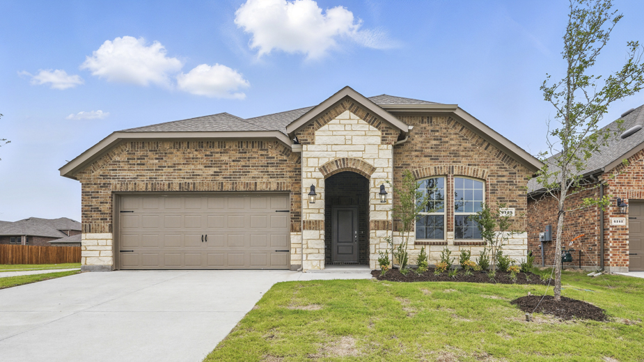Front exterior of home with two car garage and brick siding.