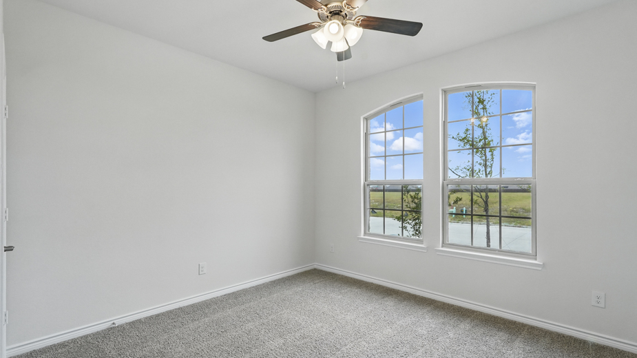 Bedroom with several large windows and carpeted floors.