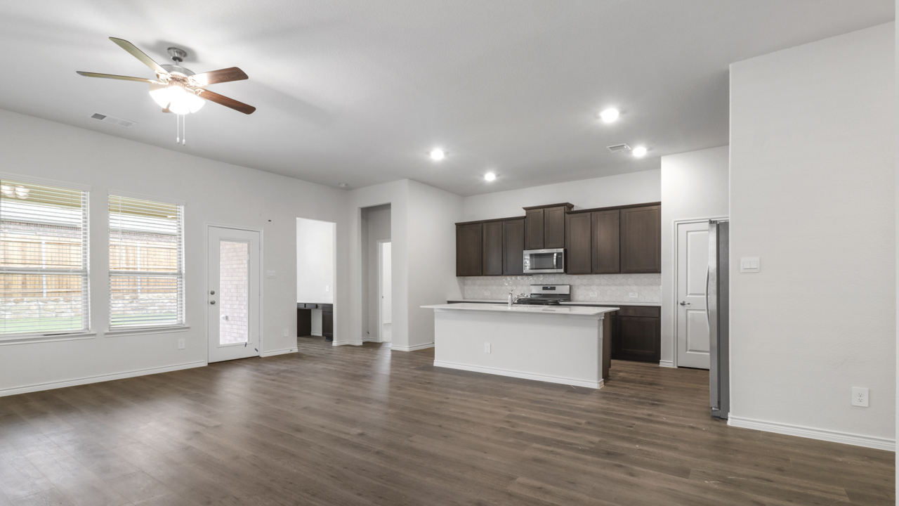 Living room with windows and kitchen with brown cabinets