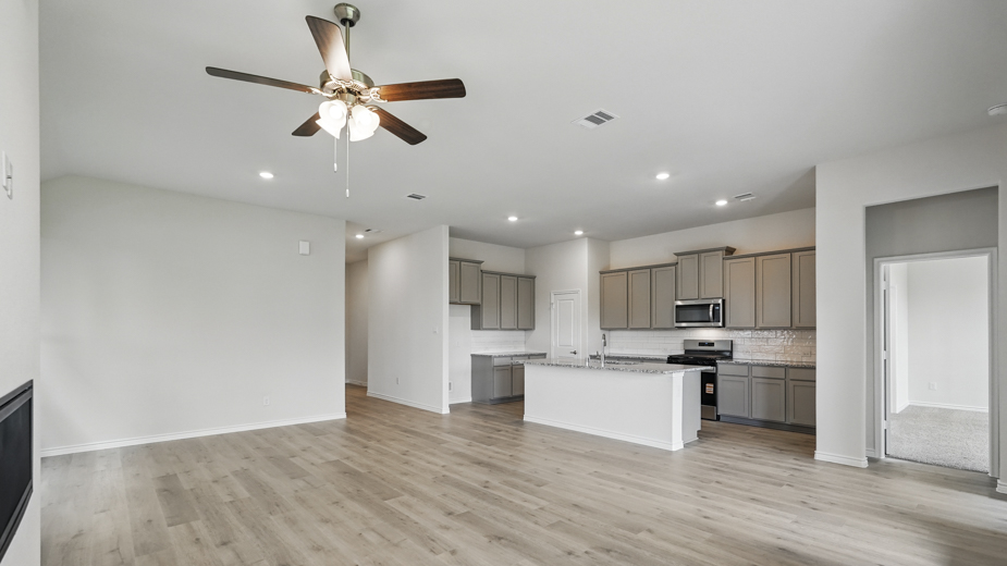 Living room with windows and kitchen with brown cabinets