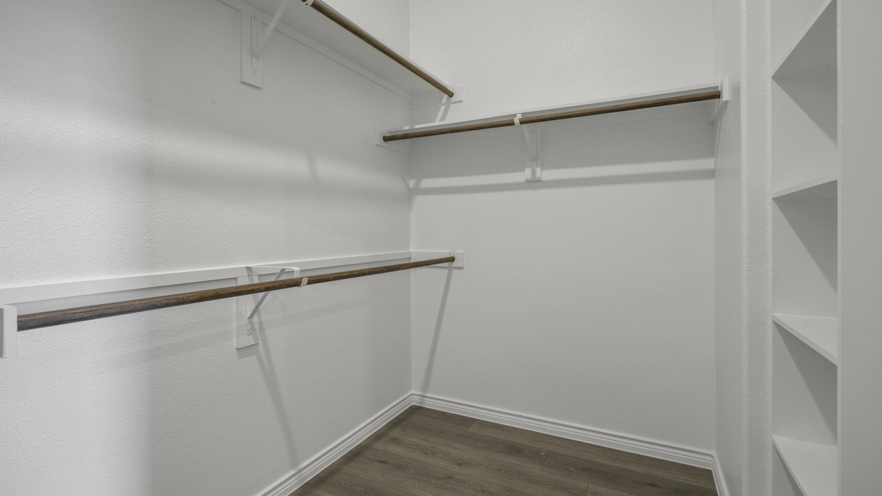 primary bathroom walk in closet with hanging rods and shelves