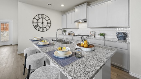 large kitchen with island and gray counters white cabinets and stainless steel appliances