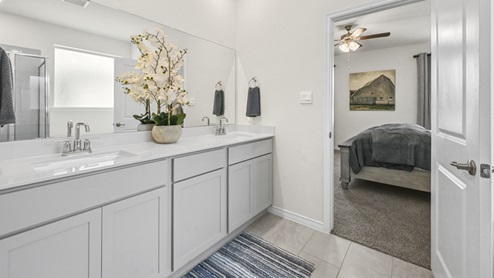 primary bathroom with elongated vanity with white cabinets and vanity length mirror