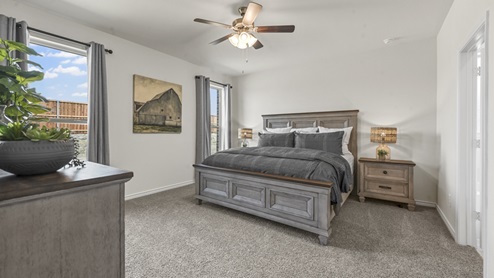 large primary bedroom with two windows a ceiling fan and bedroom furniture