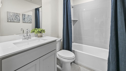 secondary bathroom with white countertop vanity and garden tub