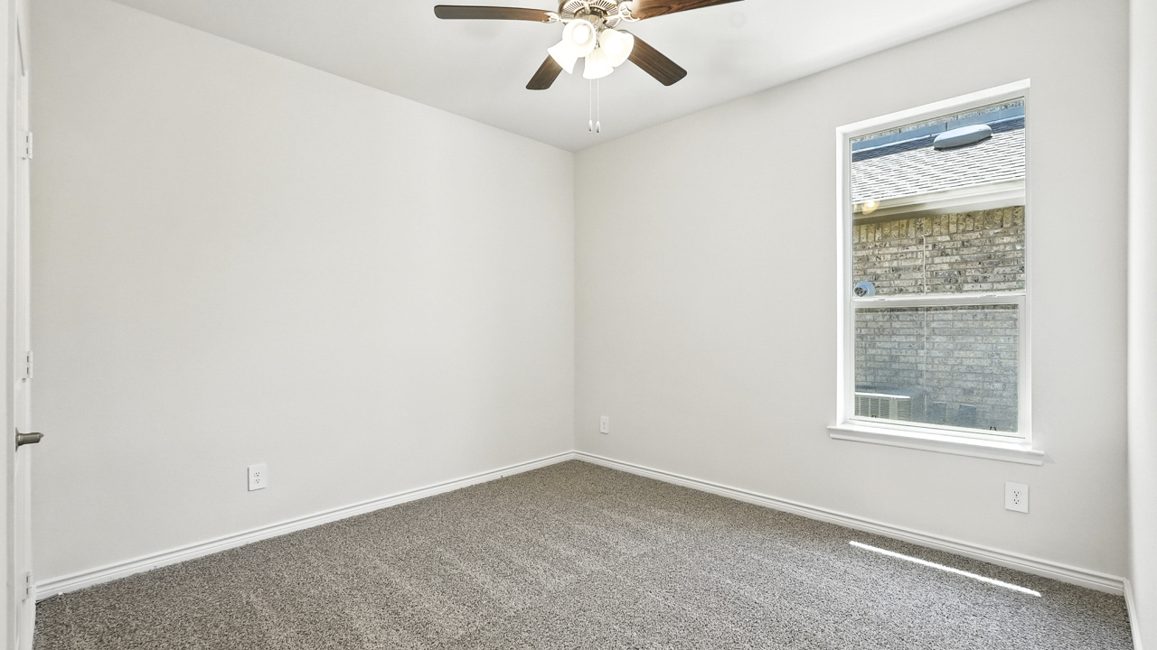 secondary bedroom with a large window and tile flooring.