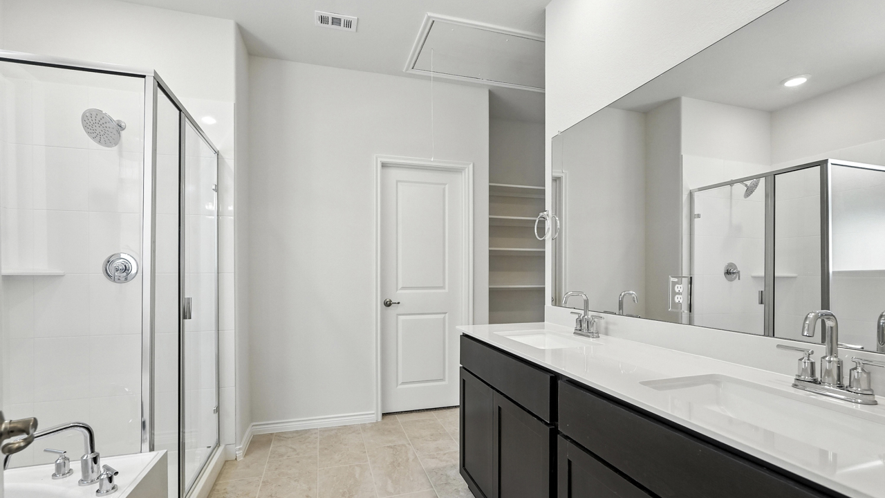 Primary bathroom tub with glass shower door next