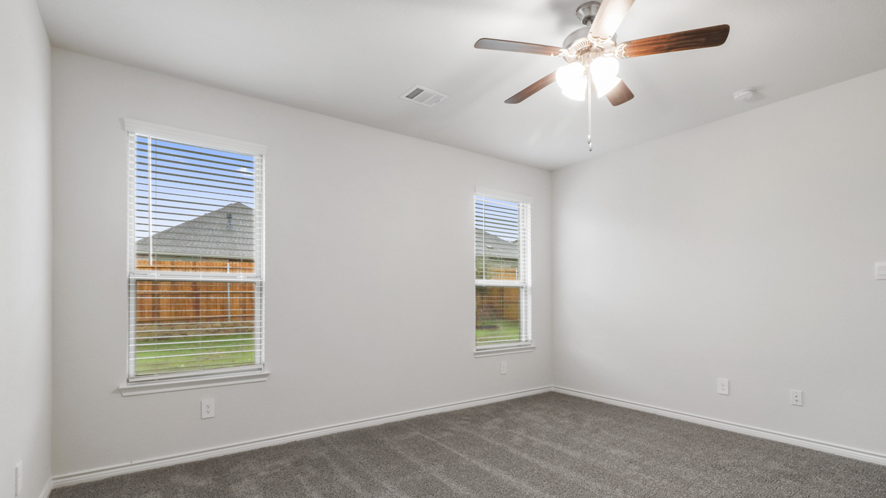 Primary bedroom with windows and ceiling fan