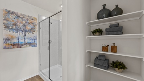 large primary bathroom with walk in shower and storage shelves