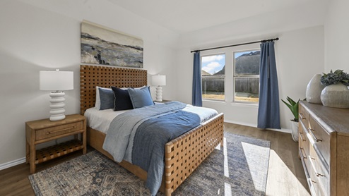 large primary bedroom with windows and blue furniture