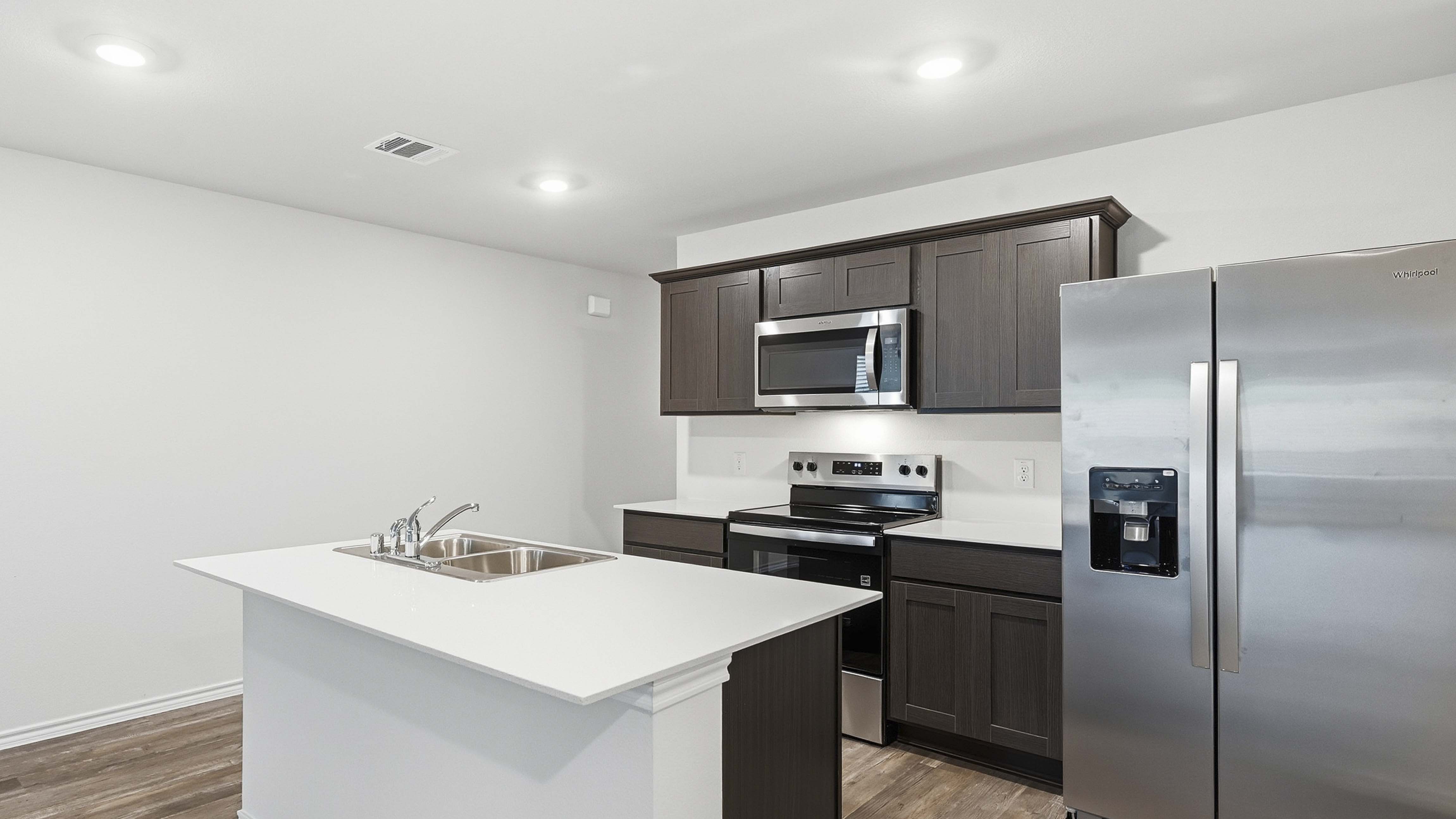 kitchen area with hardwood floors dark cabinets and white counters
