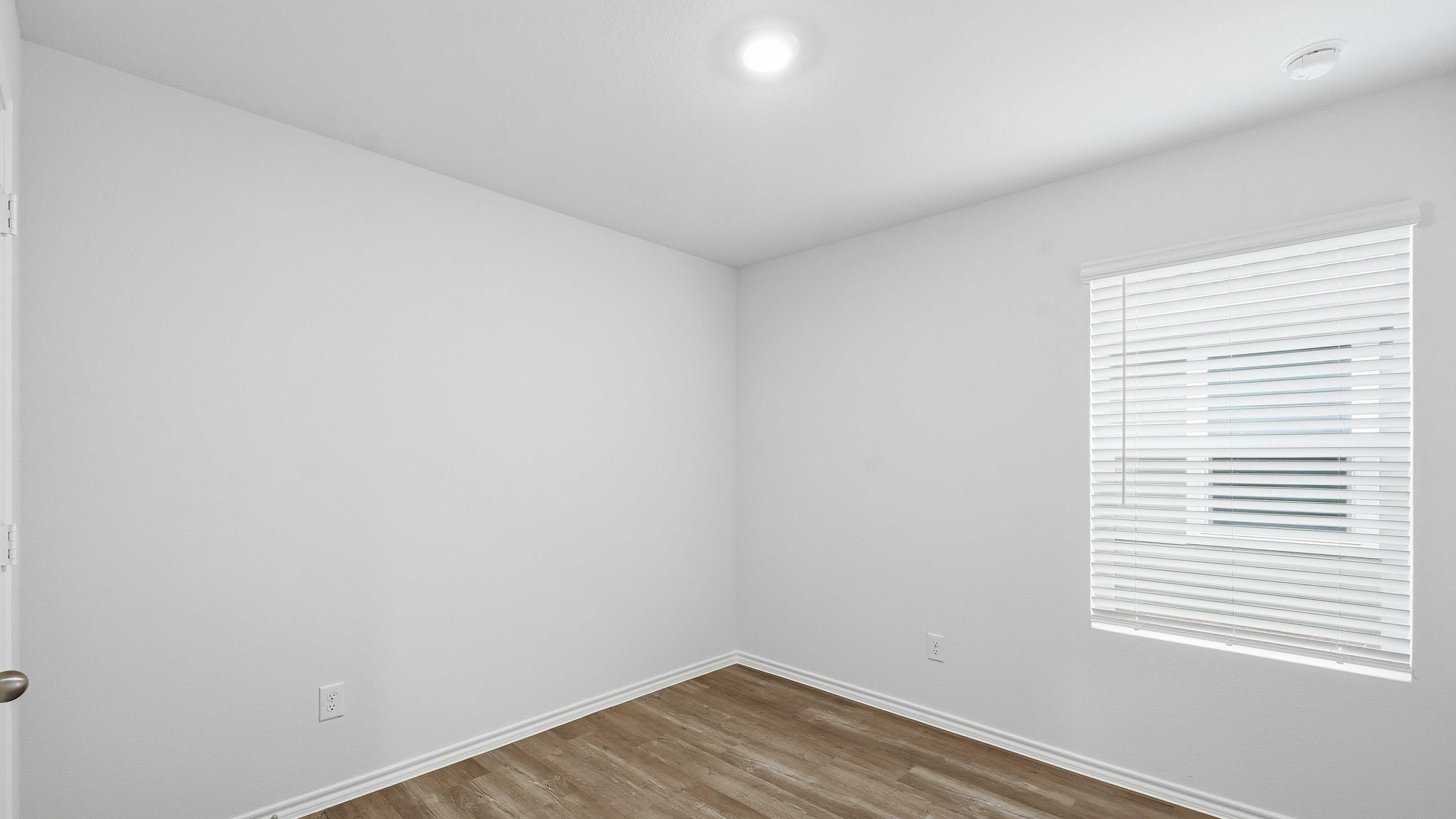 secondary bedroom with large window providing natural light and hardwood floors