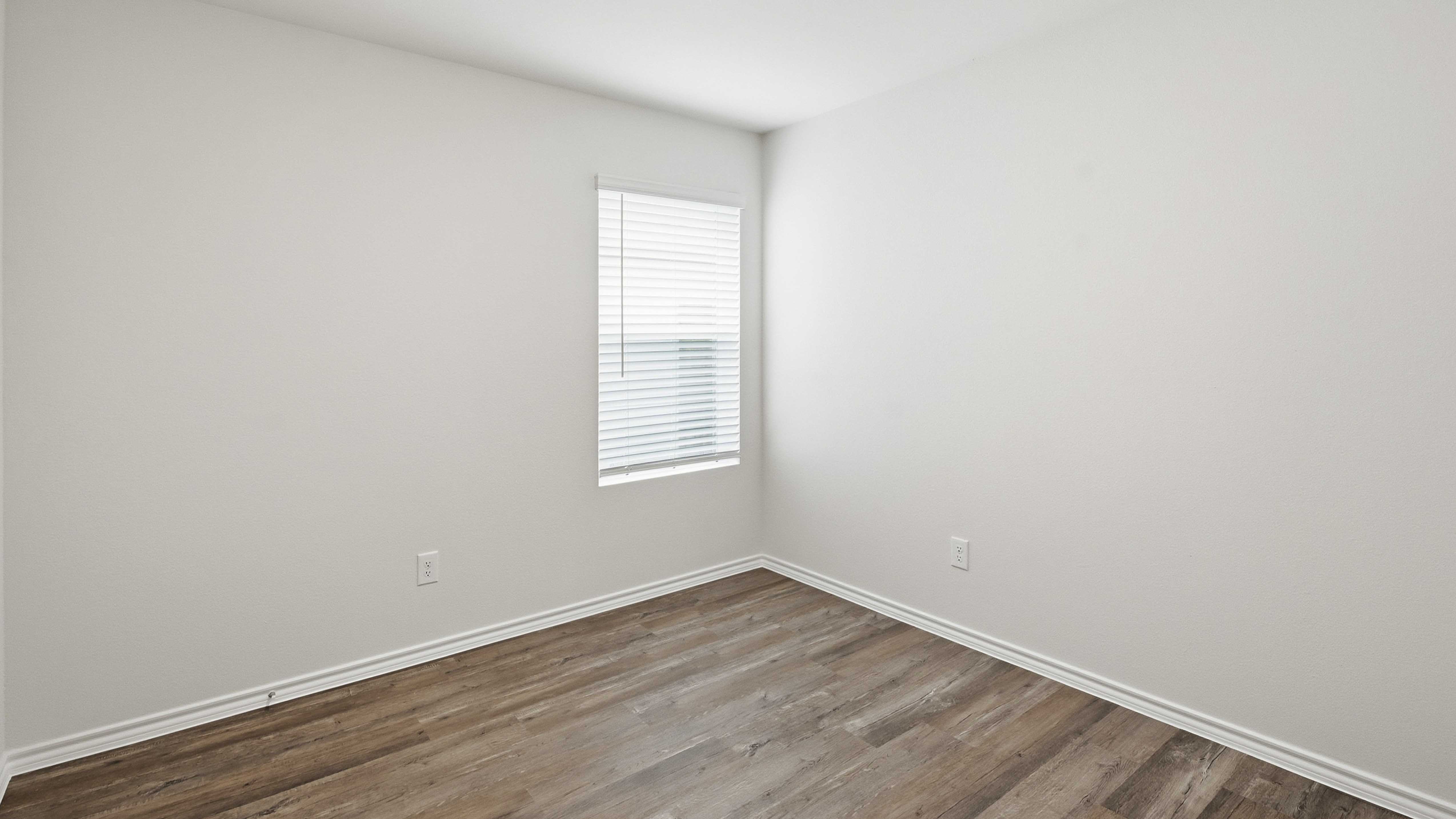 secondary bedroom with large window providing natural light and hardwood floors