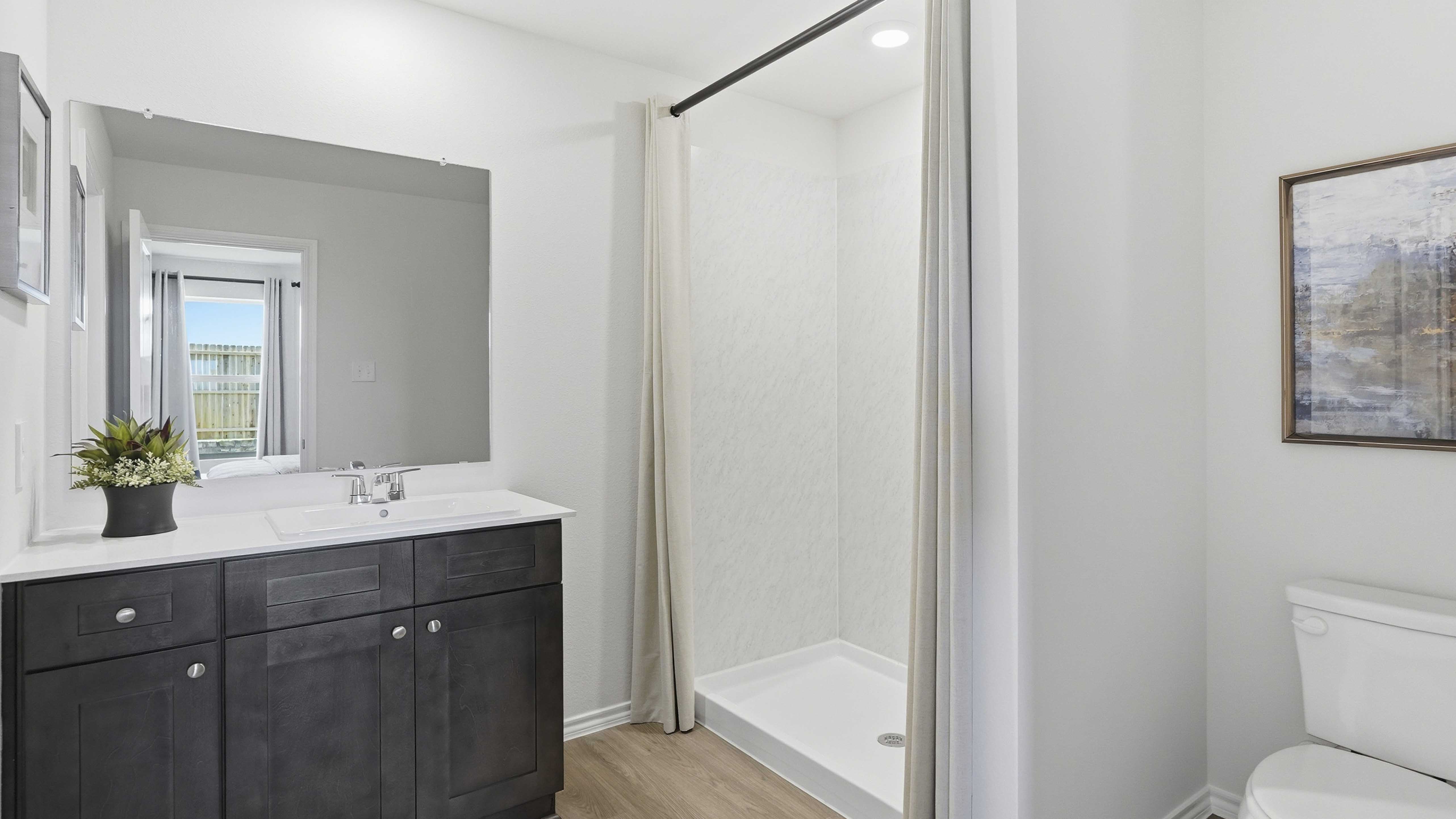 primary bathroom with hardwood floors dark cabinets and white counters