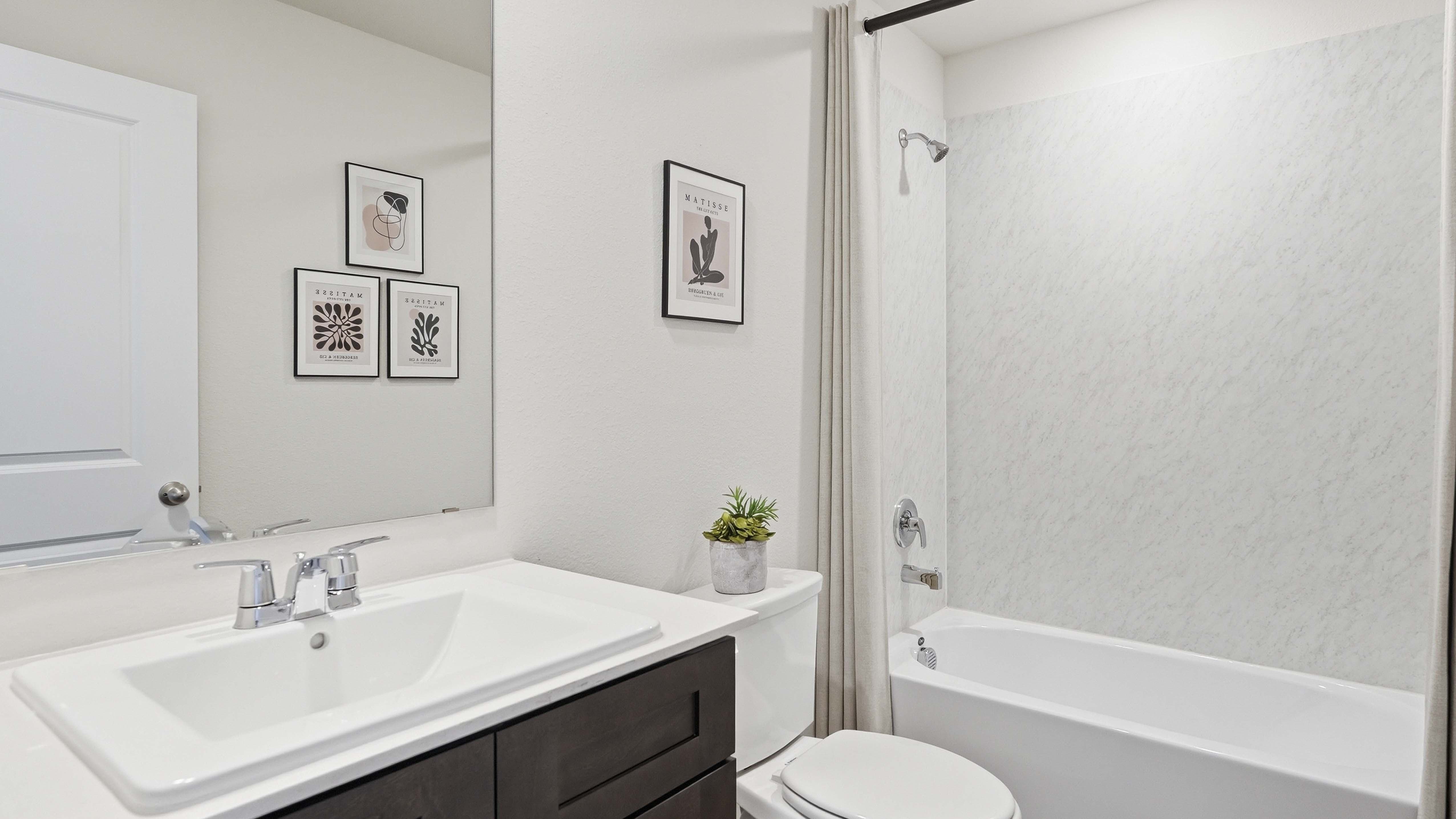 secondary bathroom with hardwood floors dark cabinets and white counters