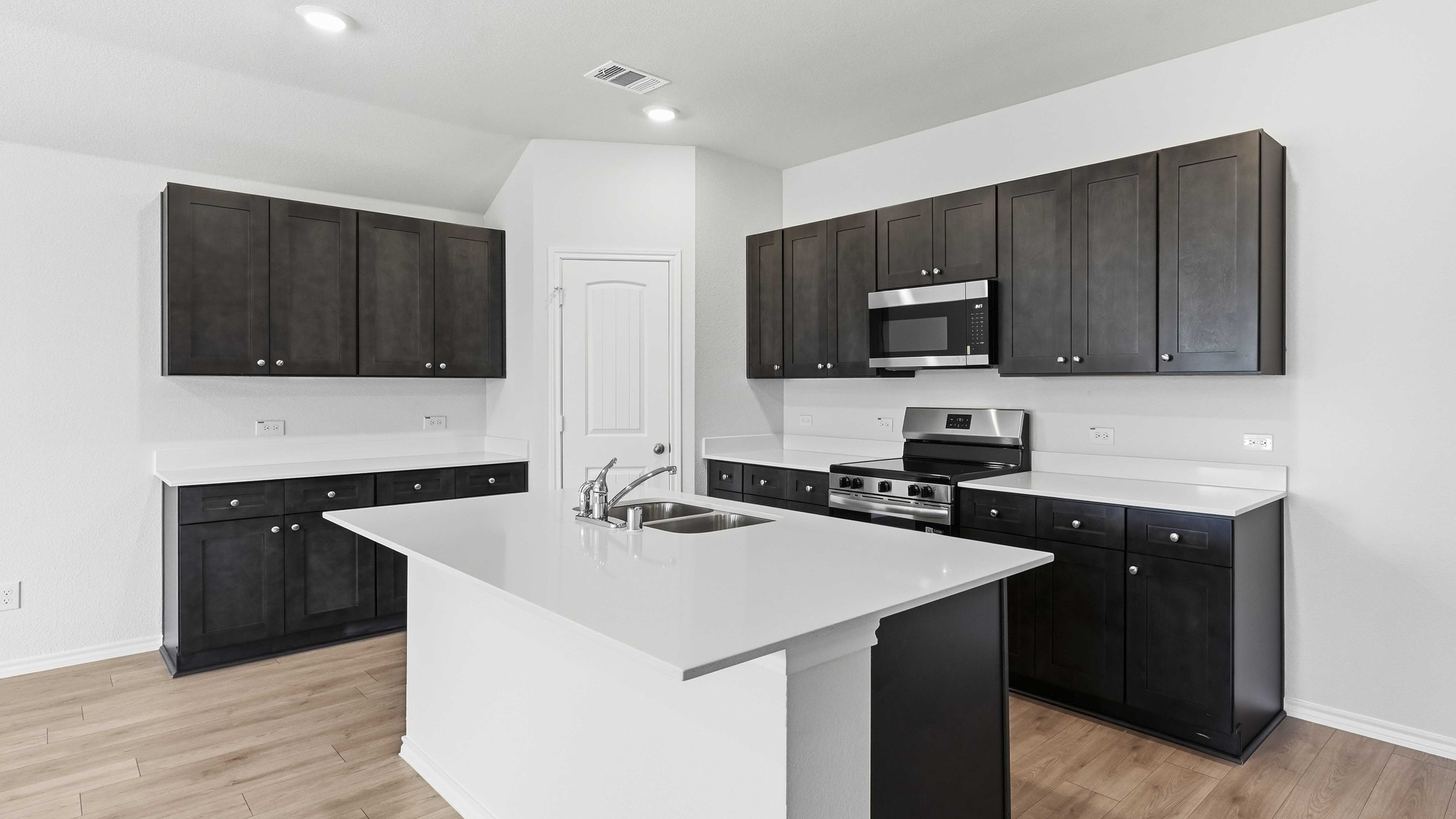 kitchen area with hardwood floors dark cabinets and white counters