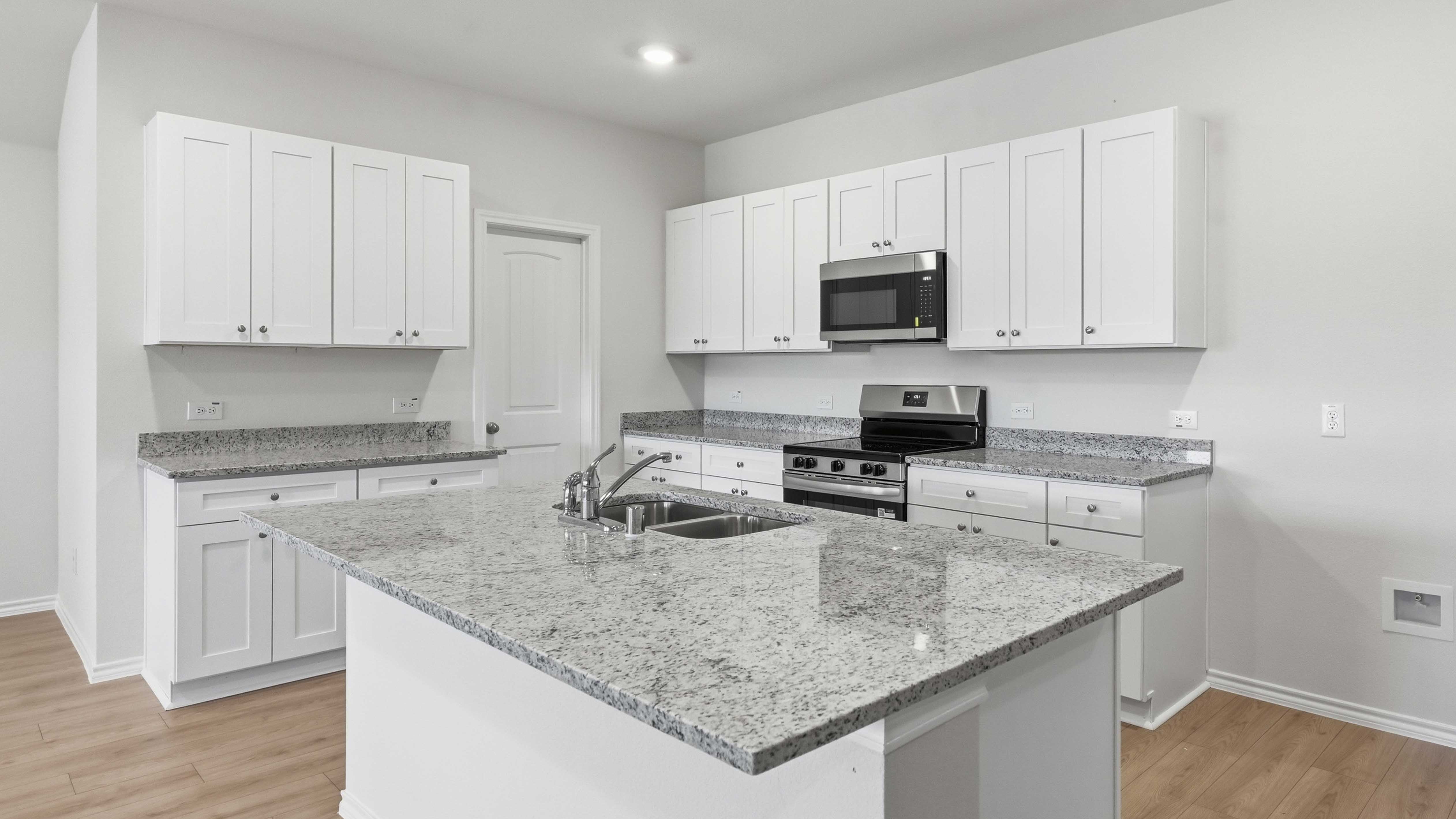 kitchen area with hardwood floors grey granite counters and white cabinets with a kitchen island