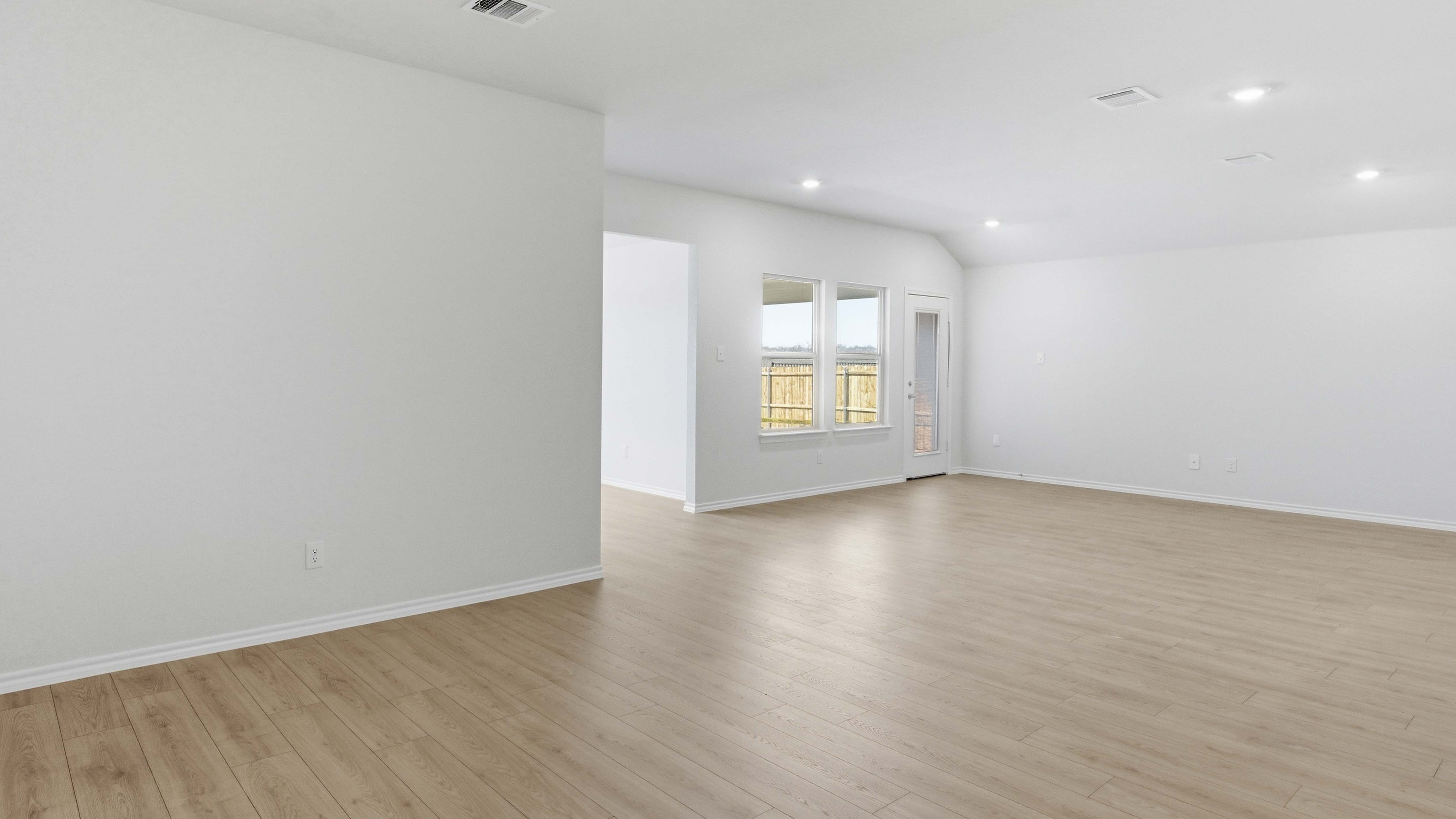 open concept living area with hardwood floors and large windows providing natural light facing the backyard