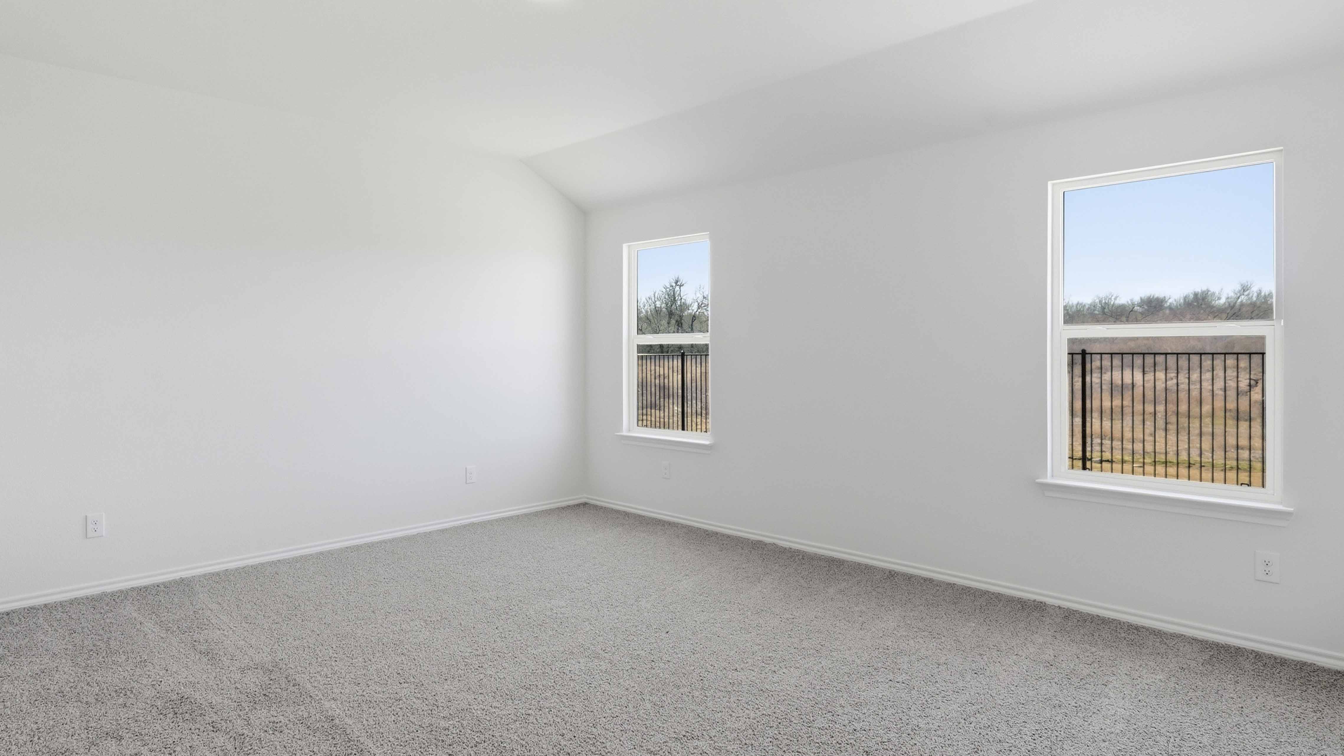 primary bedroom with carpet and large windows facing the backyard providing natural light