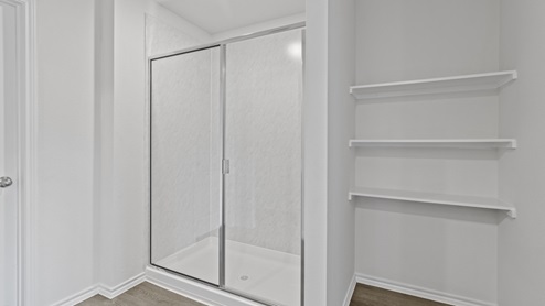 Primary bathroom with walk in shower and storage shelves