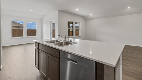 Kitchen island next to breakfast nook and living room with windows