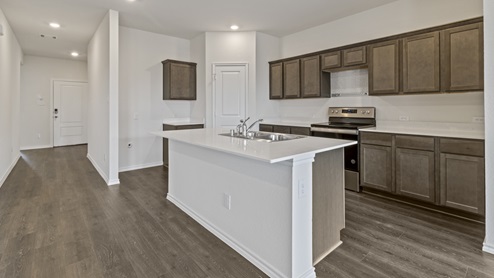 Kitchen island with brown cabinets next to entry