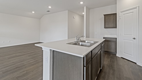 Kitchen island with brown cabinets next to entry and living area