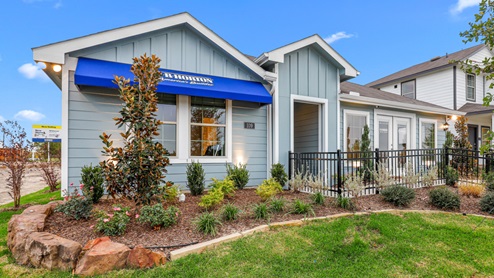 Single story model with blue siding and beautiful landscaping