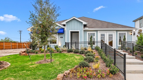 Single story model with blue siding and beautiful landscaping