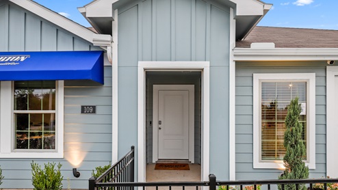 Close up of Single story model with blue siding and beautiful landscaping