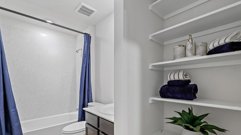 Secondary bathroom with storage shelving and garden tub