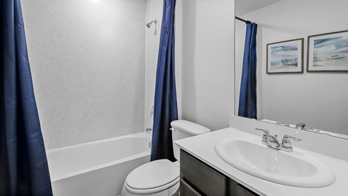 Secondary bathroom with white counter vanity and garden tub next to commode