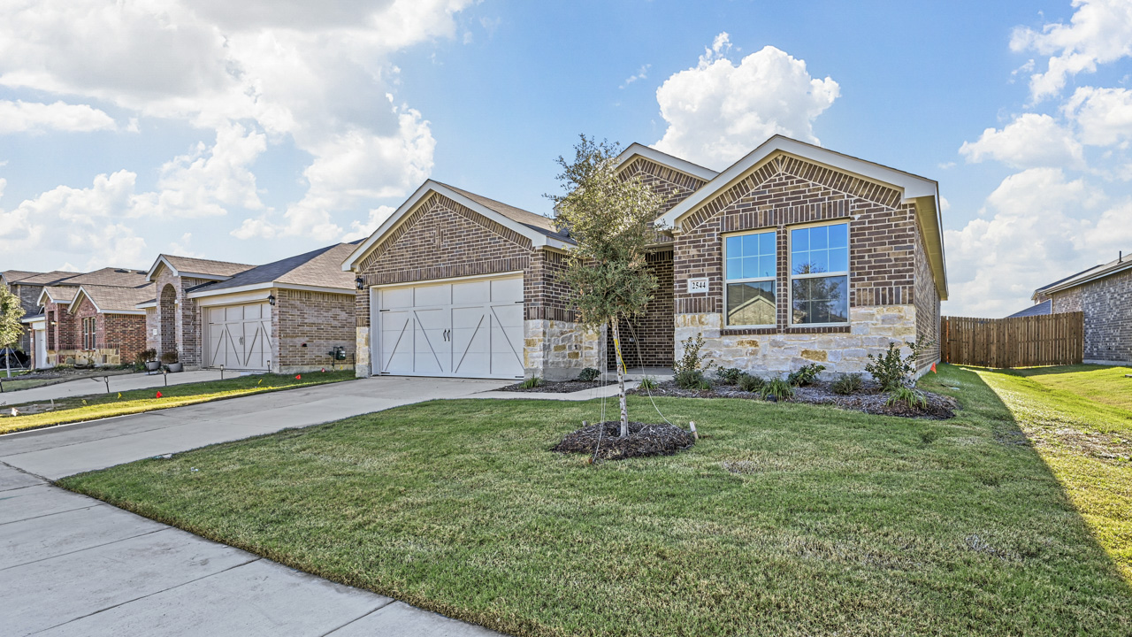 the brick exterior of a one story home with a concrete driveway and a gras covered front yard