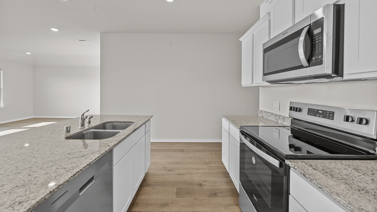 a kitchen with white cabinets an island in the middle and wood floors
